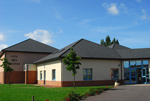 photo du bâtiment community, les murs sont blancs et le toit gris, l'espace est bordé de pelouse